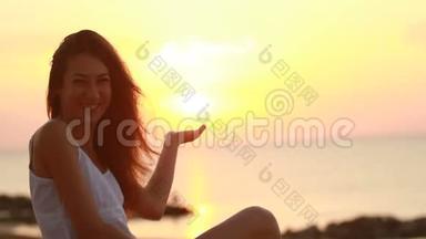 快乐的年轻女子在清晨的海滩上微笑，一边想象着和太阳玩耍的<strong>情景</strong>